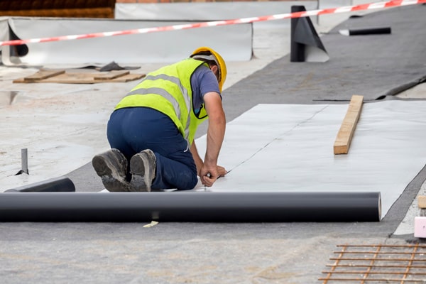 worker cutting a rolled out liner on roof